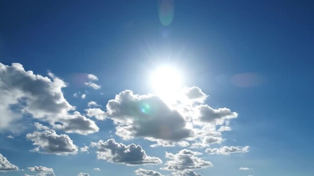 Bright Sun Shining Through Fluffy Clouds in a Clear Blue Sky