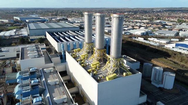 Aerial drone view of a major gas fired power station in Hoddesdon UK featuring massive industrial smoke stacks and electricity substation landscape.