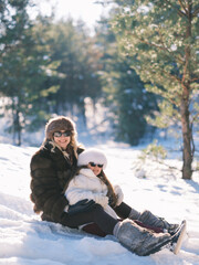 Obraz premium Mother and daughter have fun sitting on snow. Slavic style winter fashion.