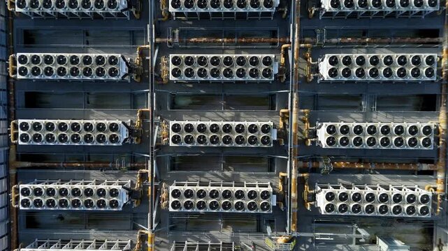 Aerial top down view of symmetrical rows of industrial cooling fans and ventilation systems on a data center rooftop for AI computing infrastructure.