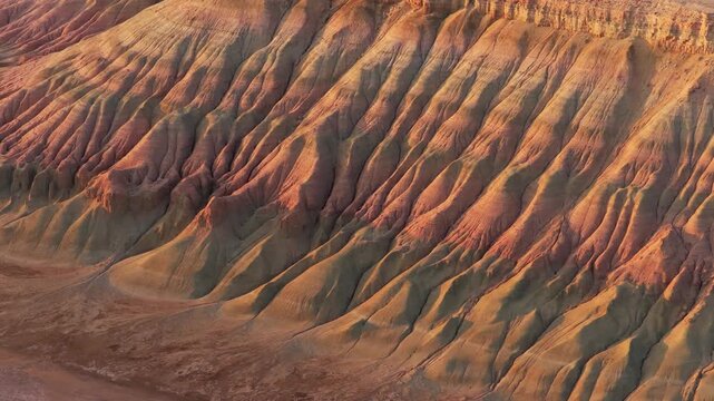 Aerial view of a landscape with striking canyon formations, showcasing textures and earthy tones under soft light, Karynzharyk, Mangystau Region, Kazakhstan.