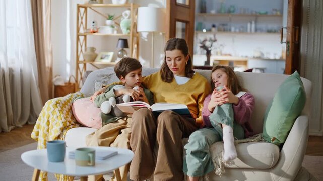 Mom kids enjoying book sofa enjoying family weekend. Mother reading fairytale