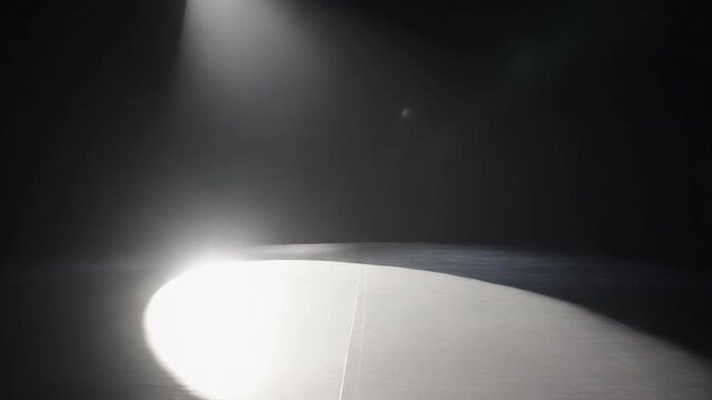 Empty dark stage with moving overhead spotlights sweeping across wooden floor in smoky theater