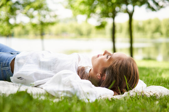 Relaxed young woman daydreaming in park with eyes closed