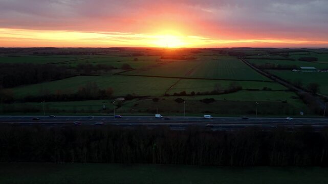Aerial Sunset Hyperlapse of Busy A1 Motorway in UK, Golden Light Over Fast Traffic and Expansive Rural Landscape in British Countryside, 4K Drone