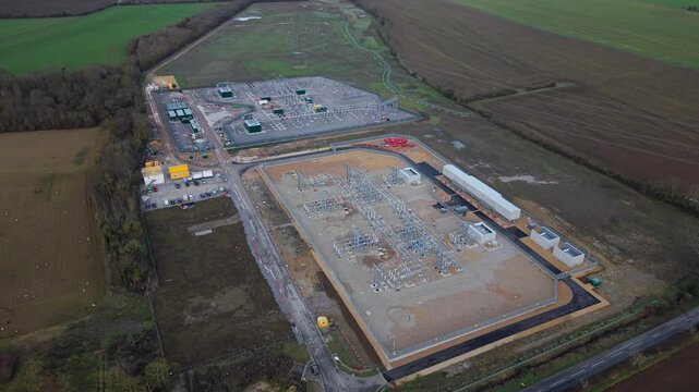 Close up aerial view of 400kV substation featuring supergrid transformers and high voltage pylons for the Great Grid Upgrade near Biggleswade United Kingdom. 