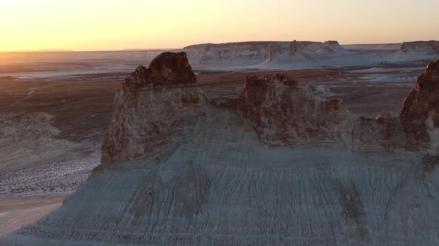 Aerial view of striking rock formations with contrasting light and shadow, a barren landscape under a pastel sky, Aktau, Mangystau Region, Kazakhstan.