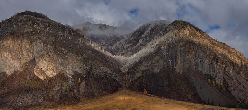 Russia. The South of Western Siberia, the Altai Mountains. A fascinating view of the mountains with yellow larches, dusted with the first autumn snow, along the Chuya highway in the valley of the Chuy