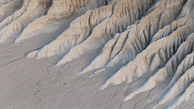 Aerial view of the chalk cliffs in Tuzbair, where light and shadow play across the textured landscape, showcasing nature's raw beauty, Tuzbair, Mangystau Region, Kazakhstan.