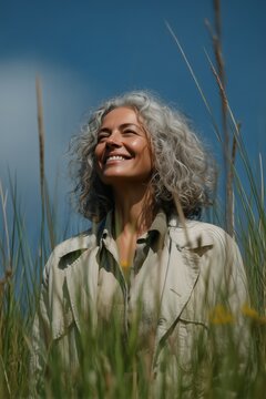 Mujer madura pelo gris rizado sonriendo al cielo entre juncos, Recurso editorial lifestyle para bienestar y naturaleza, Mockup de mujer sonriente para publicidad de envejecimiento activo