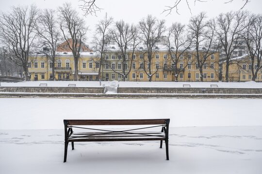 Bench and historic buildings on the frozen Aurajoki river, wintery Turku or Swedish &Aring;bo, Varsinais-Suomi, Finland