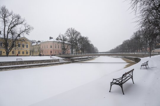 Benches, historic buildings on the frozen Aurajoki River, wintery Turku or Swedish &Aring;bo, Varsinais-Suomi, Finland