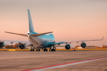Fototapeta premium Large cargo airplane taxiing on airport runway for take off in warm afternoon light. Air freight, logistics, and global transportation concept.