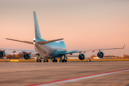 Large cargo airplane taxiing on airport runway for take off in warm afternoon light. Air freight, logistics, and global transportation concept.