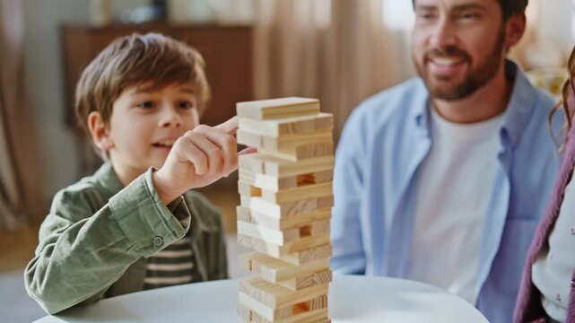 Happy boy playing jenga with parents home closeup. Smiling father supporting kid