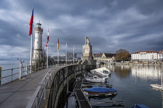 Lion pier with boats and Bavarian lion, in the back New Lindau lighthouse, Lindau harbour entrance, Lindau island, Lake Constance, Bavaria, Germany