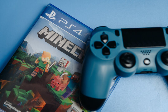 KIROV, RUSSIA - JANUARY 10, 2026 game console disk in package and gamepad lying on blue table, Minecraft for Playstation 4, cropped, selective focus