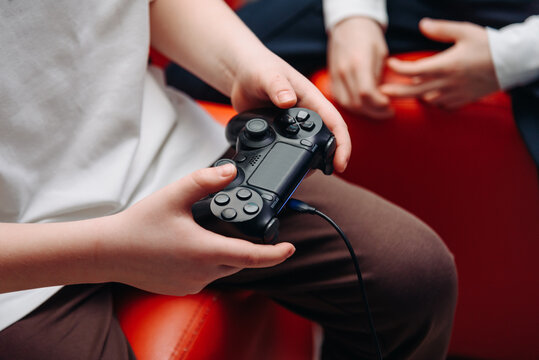 black gamepad in hands, young boy playing game console, selective focus