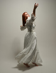 full length portrait redhead female model wearing historical fantasy wedding dress, fairytale ball gown.  posing walking away from camera, isolated figure on white studio background © faestock