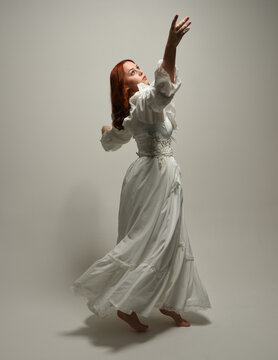 full length portrait redhead female model wearing historical fantasy wedding dress, fairytale ball gown.  posing walking away from camera, isolated figure on white studio background