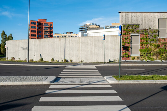 Empty urban city street crosswalk for pedestrian crossing on road showing transport access with modern architecture under clear sky