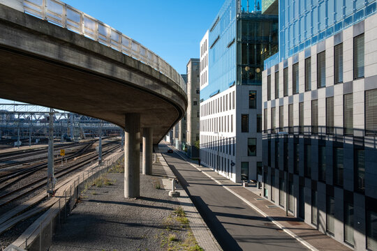 Modern city roadway ramp beside rail tracks under bridge showing transport architecture with strong perspective and empty corridor urban