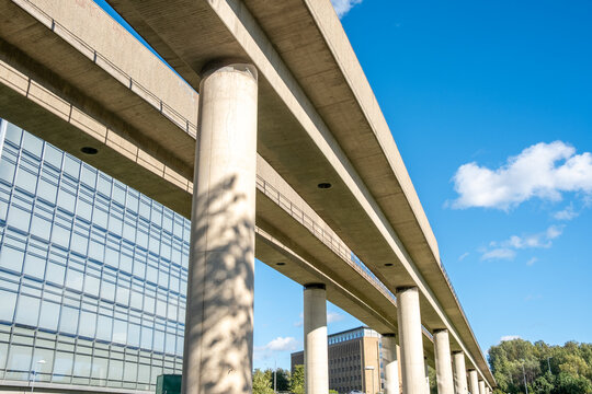 Modern city building of glass beneath viaduct columns showing transport architecture and engineering under clear sky strong perspective