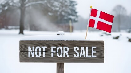 A wooden sign covered in snow with the phrase "not for sale" and a small Danish flag stuck into it.