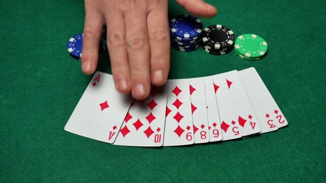 The hand reveals playing cards of the same suit, all diamonds, and that is a win. Nearby, on a green table, poker chips are stacked in piles.