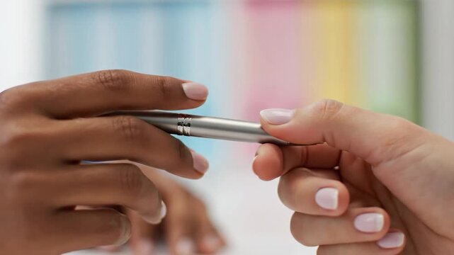 Close-up of hand holding silver pen with blurred colorful background
