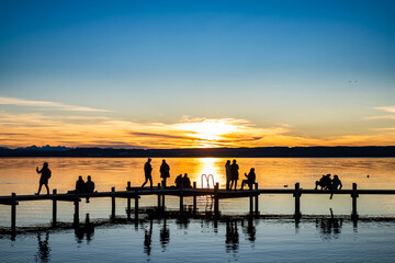 wooden pier with mountains in the distance, reflecting on calm water in the early morning light
