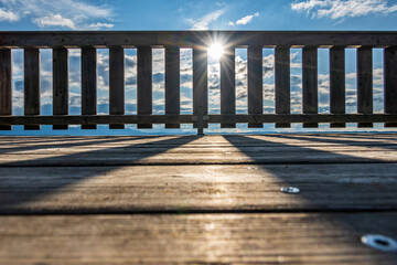 wooden pier with mountains in the distance, reflecting on calm water in the early morning light