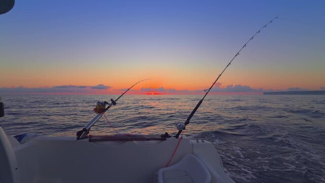 Offshore trolling fishing at sunset with rods on boat in open sea