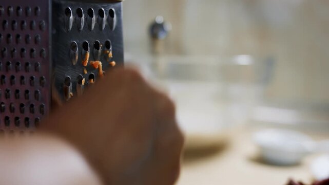 Female hand grating carrots on a grater in the home kitchen
