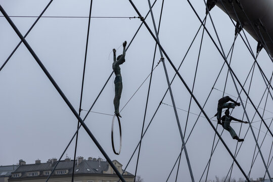 Krakow, Poland - December 2, 2025: Jerzy Kedziora Balancing Sculptures depict acrobats defying gravity on metal rings against a cloudy sky