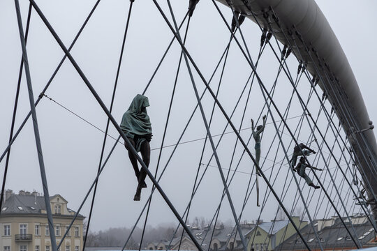 Krakow, Poland - December 2, 2025: Jerzy Kedziora's Balancing Sculptures on Bridge Cables Conveying Artistry and Delicate Equilibrium Amidst Architecture