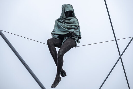 Krakow, Poland - December 2, 2025: Jerzy Kedziora's Balancing Sculptures depicted as a veiled figure sitting precariously on wires, symbolizing equilibrium and precariousness