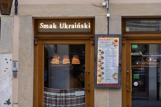 Krakow, Poland - December 2, 2025: Smak Ukrainski restaurant facade, featuring an illuminated sign and an inviting outdoor menu board, showcasing authentic Ukrainian cuisine