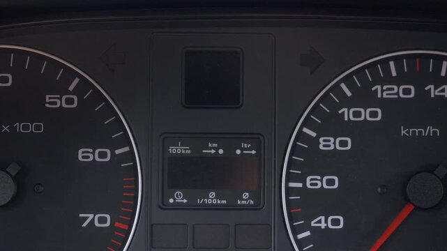 Close-up of car dashboard with tachometer and speedometer flashing and turning green crash lights on and off to signal an emergency or breakdown