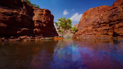 Sunlight dances on the surface of tranquil waters surrounded by stunning red rock formations. A solitary tree stands proudly, adding life to the breathtaking landscape.