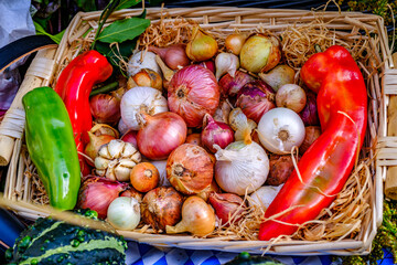 Fresh vegetables and herbs in a wicker basket displayed at a market during the day