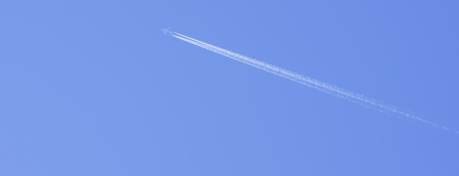 avi&oacute;n blanco vuela alto por el cielo azul dejando una estela de nubes mientras viaja r&aacute;pido
