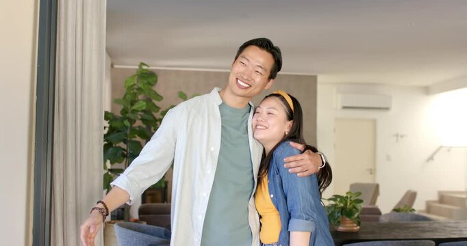 Diverse couple arriving at entrance, entering home while woman holding keyring celebrating new home