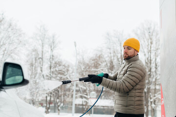 Man washing electric car in winter