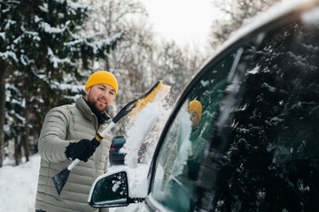 Driver clearing snow from electric vehicle in winter