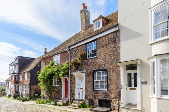 Old brick houses along a cobblestone street in a small historic town in the English countryside on a sunny spring day