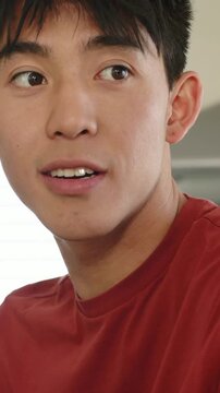 Vertical video: Reacting to offscreen voice man in red tee turning head holding ridged mug kitchen