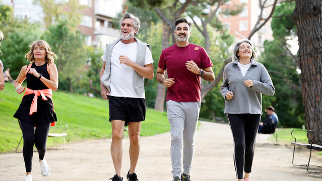 Mature friends enjoying an active lifestyle, jogging together for fitness and healthy aging in a green urban park