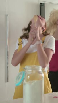 Vertical video: Grabbing spoon, teen in yellow overalls dancing and singing while baking at counter