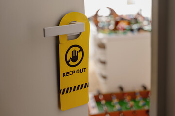 Yellow keep out door hanger sign on child&rsquo;s bedroom door handle